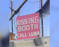 Tourists Spot ‘Kissing Booth’ Sign On Docked Boat — Then A Sweet Dog Pops Into View